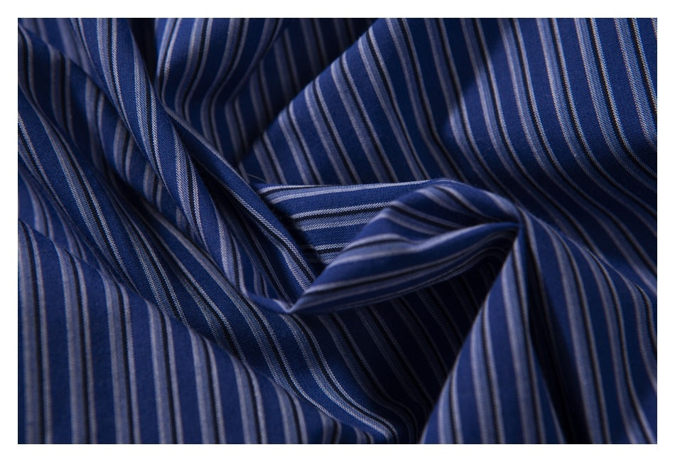 Close-up of navy fabric with narrow light blue and white stripes, softly gathered to show its texture.