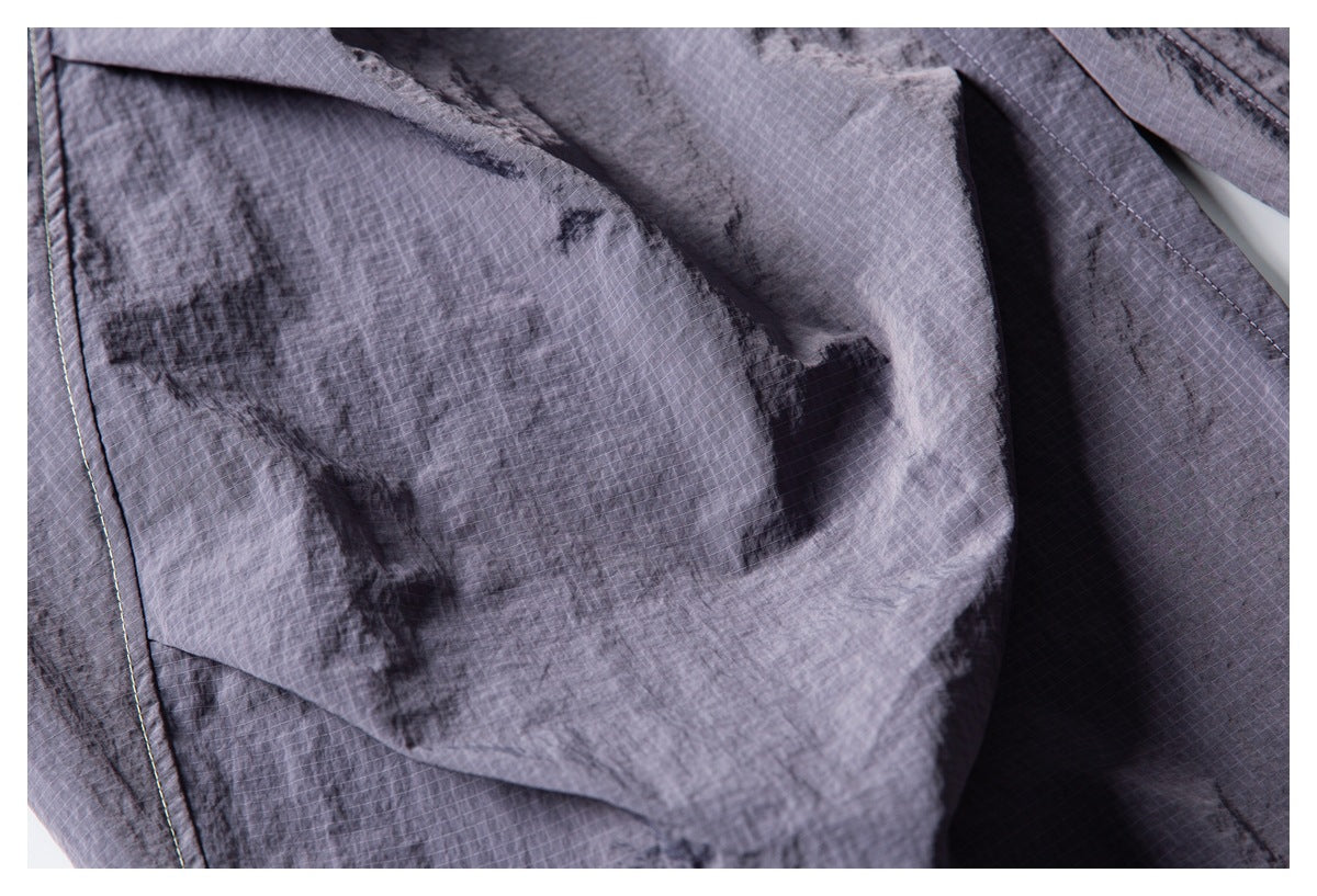 Close-up of charcoal-gray grid-textured garment fabric with folded panels and visible stitching.