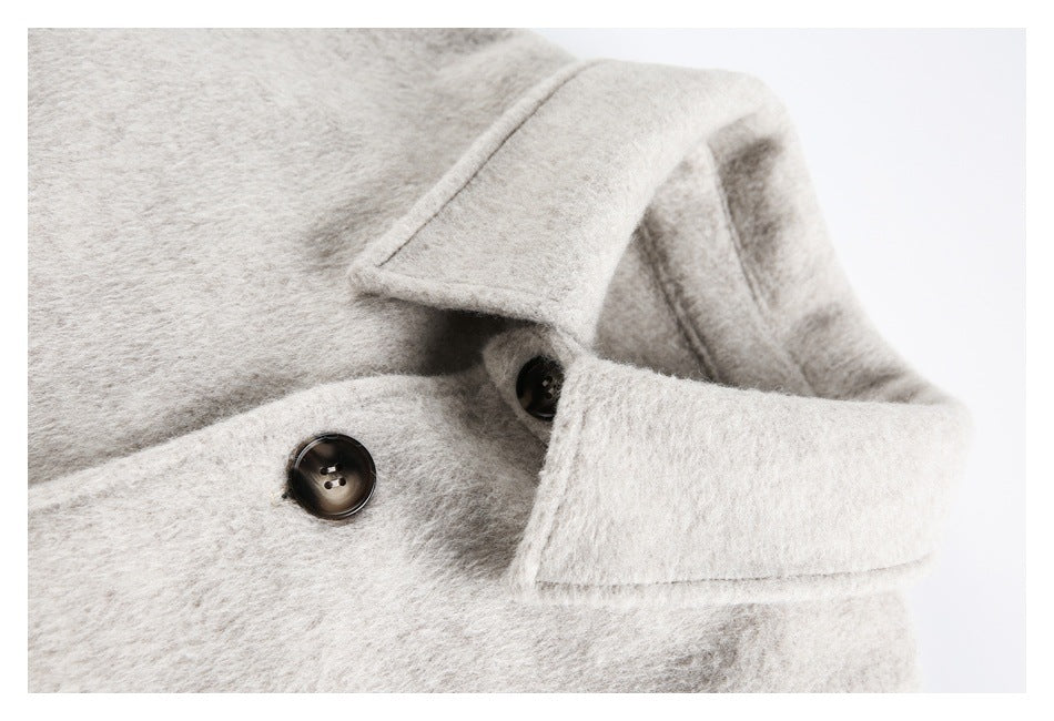 Close-up of a cream coat collar, lapel, and dark buttons.