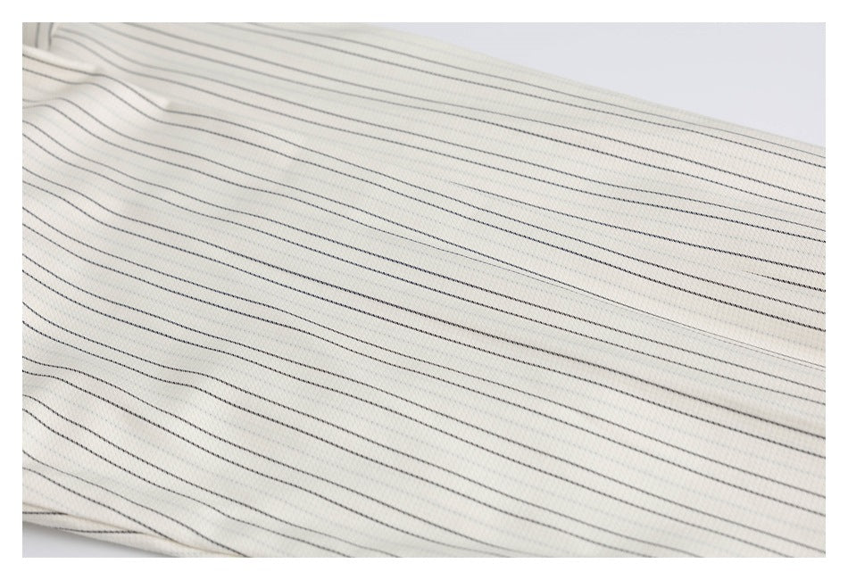 Close-up of cream fabric with fine, parallel dark pinstripes.