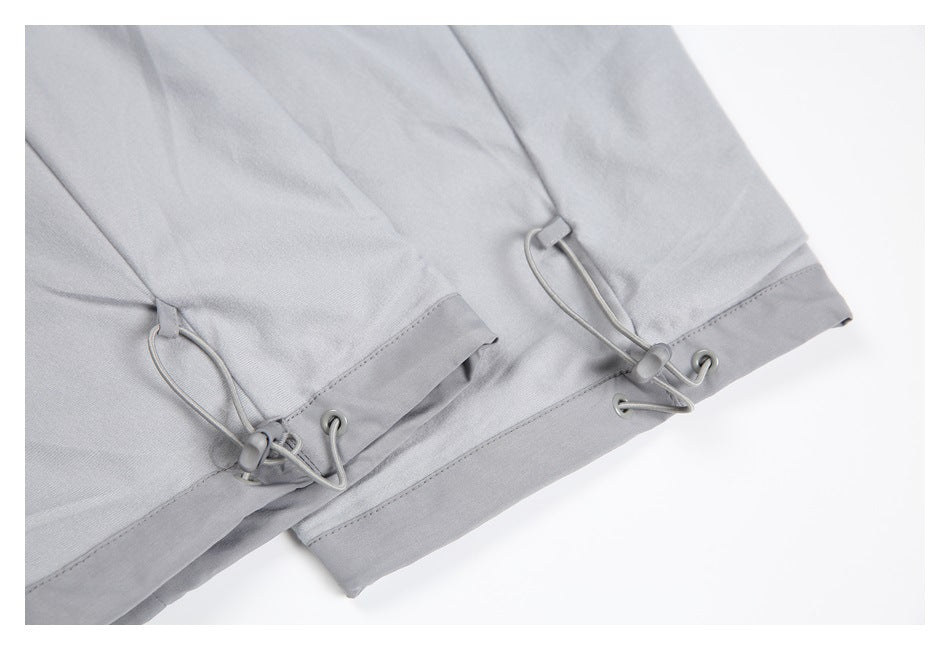Close-up of light gray garment hems with adjustable drawcords and cord locks.