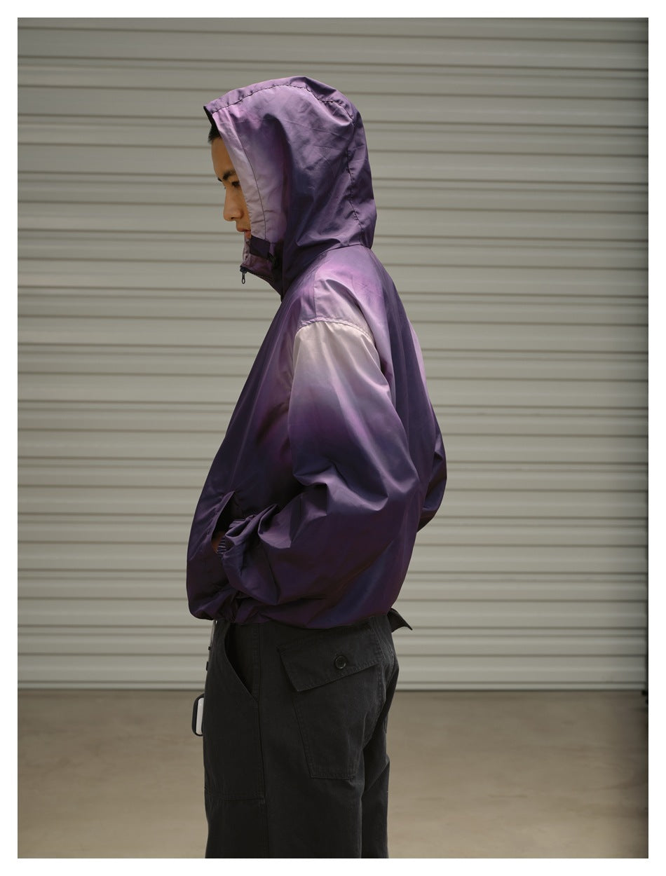 Side view of a model wearing a purple hooded zip jacket with the hood up and hands in the pockets.
