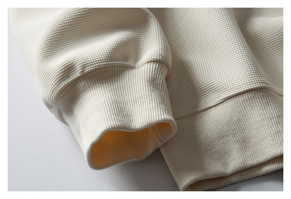 Close-up of the ivory sweatshirt's textured sleeve, ribbed cuff and lower hem.