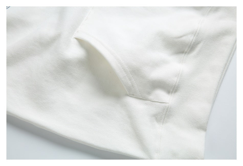 Close-up of white garment fabric with a stitched seam and folded edge.