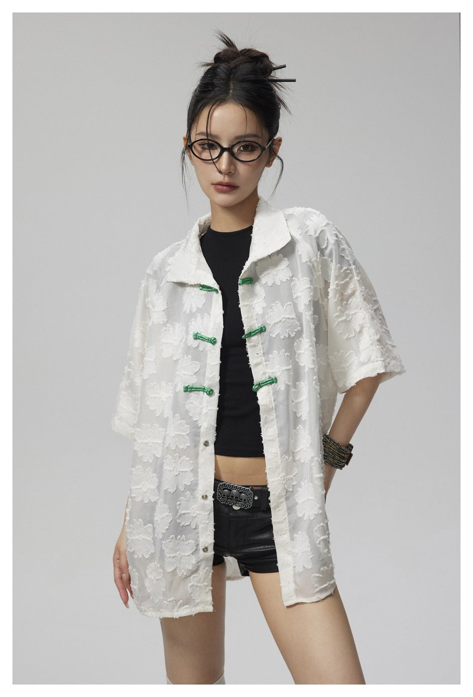 Closer view of a model wearing a white floral shirt with a pointed collar and green frog closures.