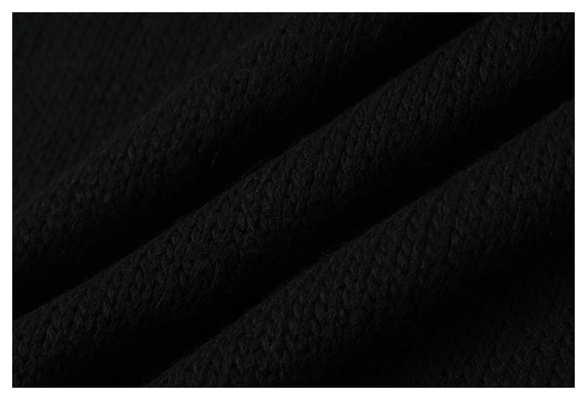 Extreme close-up of black knit fabric arranged in soft folds, showing its textured stitches.