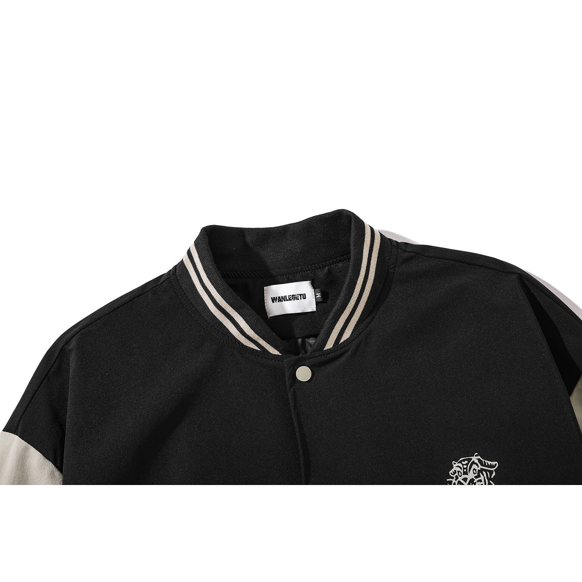 Close-up of a black varsity jacket's striped ribbed collar, snap button, small chest graphic and neck label.