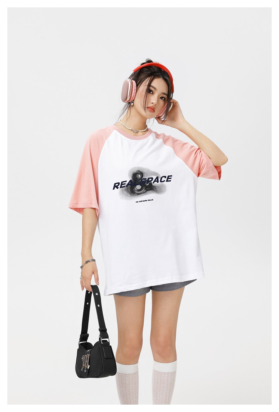 Model wearing an oversized white T-shirt with pink raglan sleeves and a large black chest graphic.