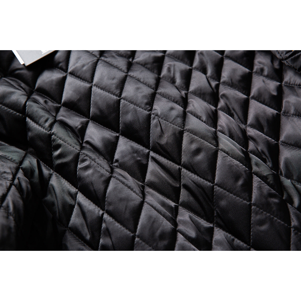 Close-up of black quilted jacket lining with a square stitched pattern.