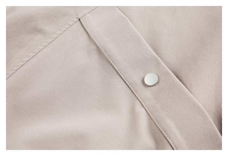 Close-up of beige jacket fabric, stitched seams, and a round silver snap fastener.