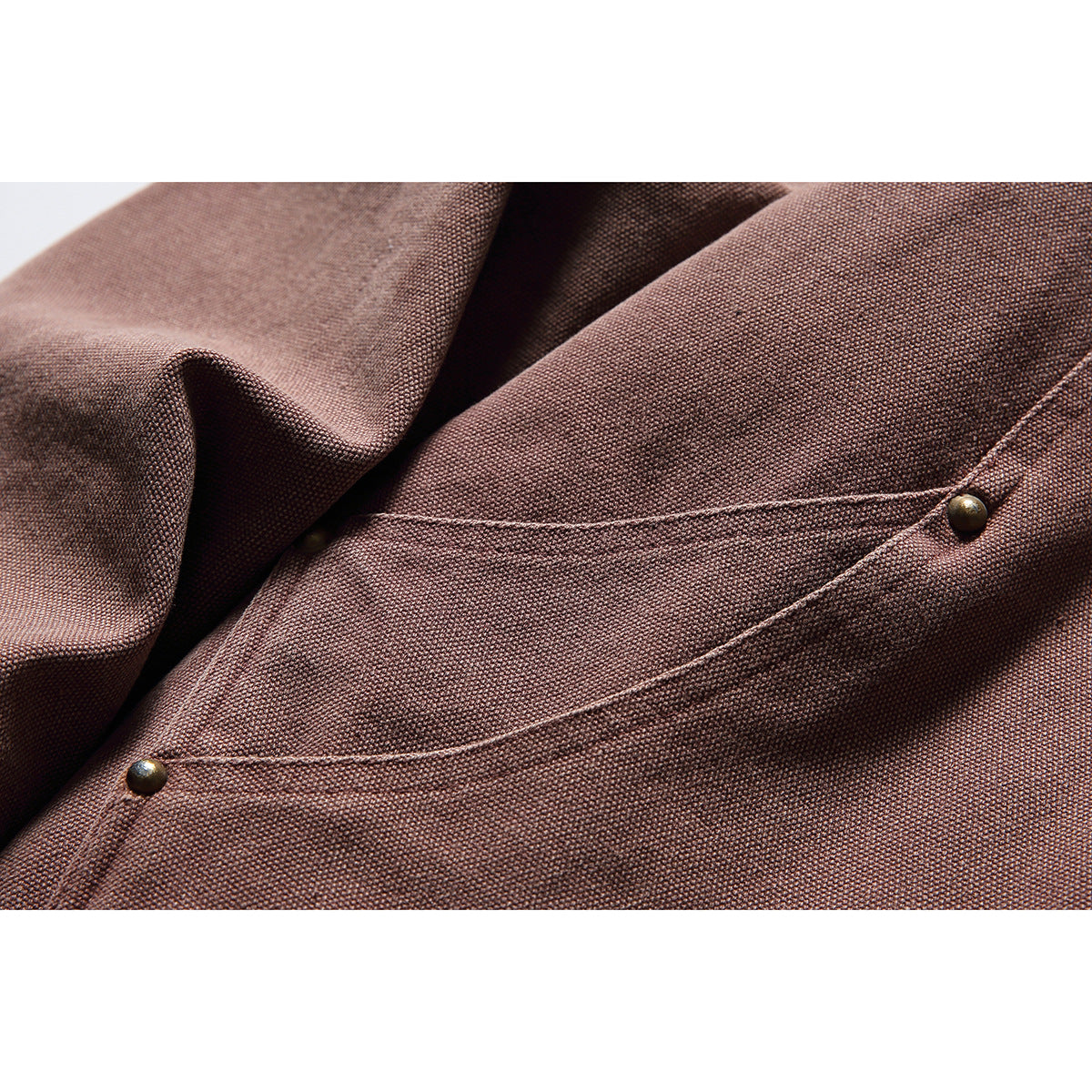 Close-up of the jacket's textured mauve-brown fabric and curved pocket seam with antique-brass snaps.