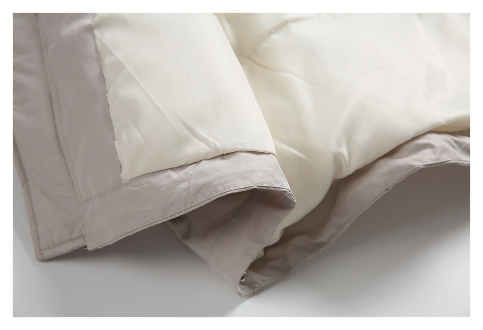 Close-up of an ivory garment edge with pale taupe trim and visible stitching.