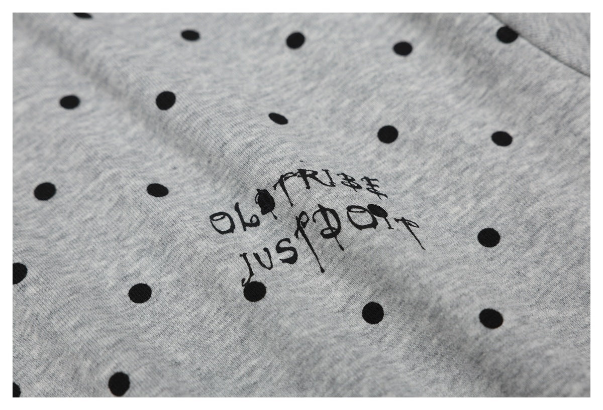 Close-up of black stylized lettering printed among the dots on a gray shirt.