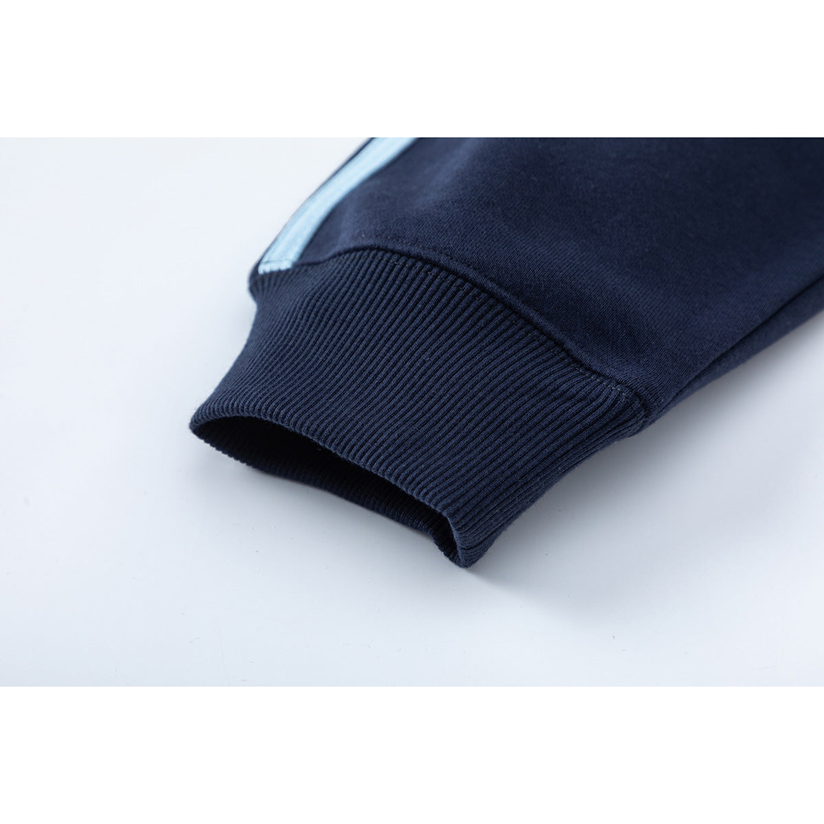 Close-up of a navy sleeve ending in a ribbed cuff, with a light blue stripe near the seam.