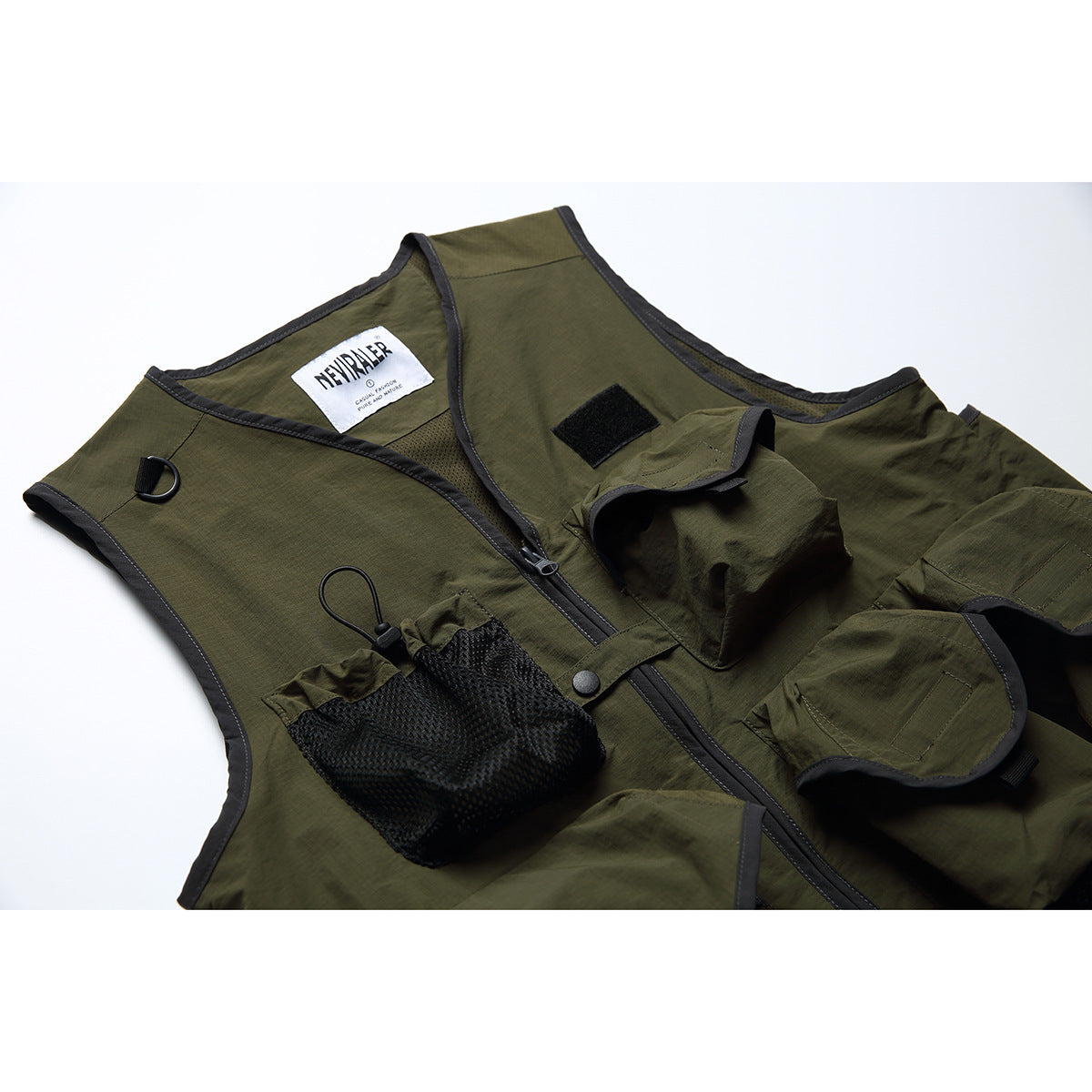 Close-up of an olive utility vest front with a zipper, mesh pocket, flap pockets, and black trim.