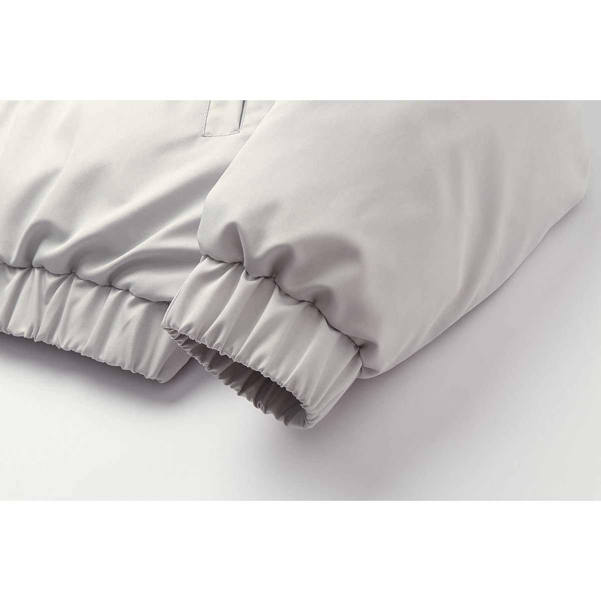Close-up of the pale gray jacket's gathered elastic hem and sleeve cuffs.
