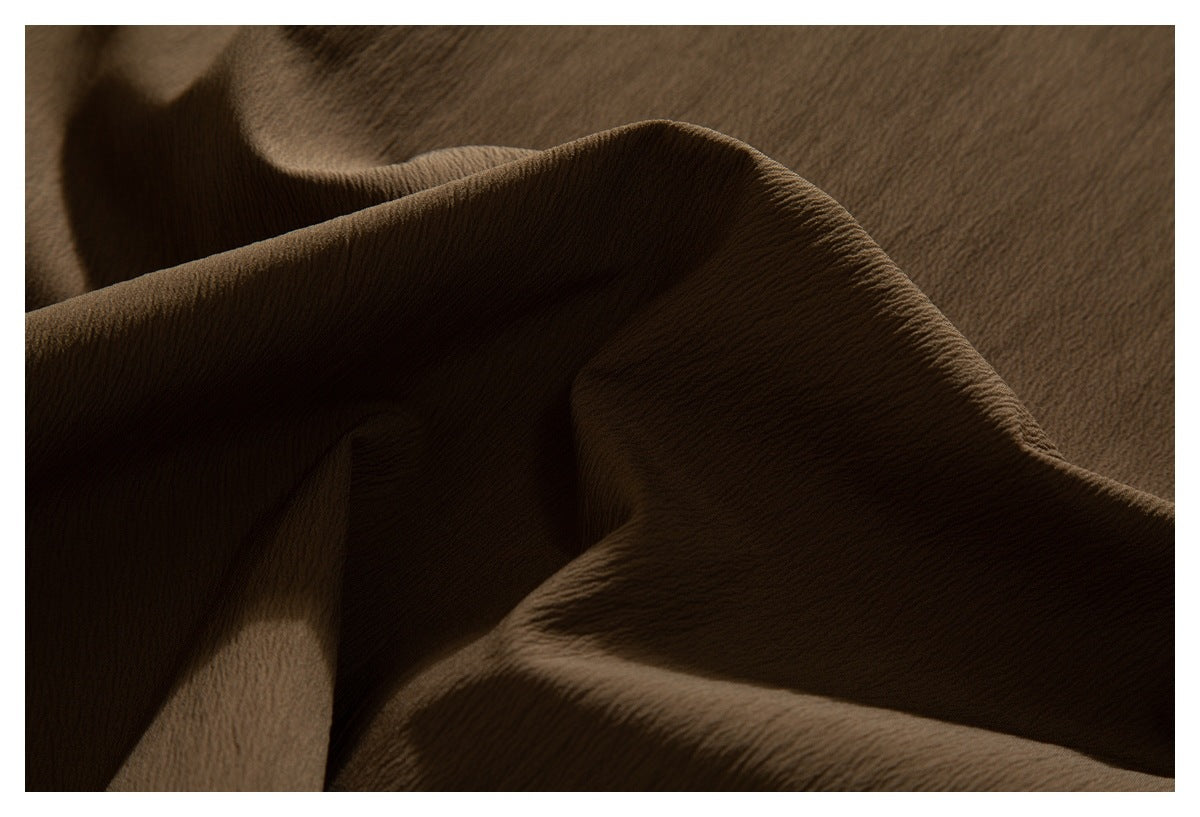 Close-up of draped brown garment fabric showing its textured surface.
