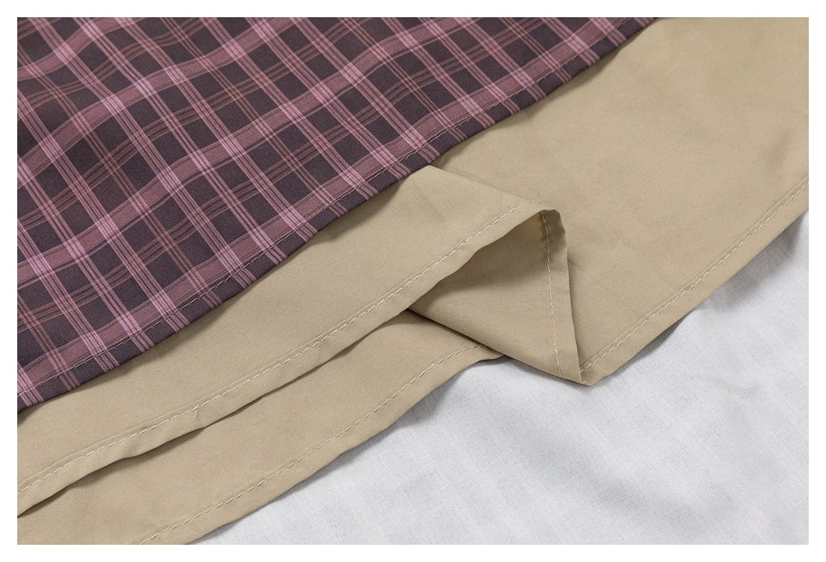 Close-up of a pink and charcoal plaid panel overlapping a khaki garment hem with visible stitching.