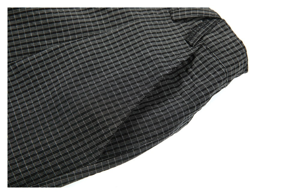 Close-up of black checked trousers showing a slanted pocket opening and seam details.