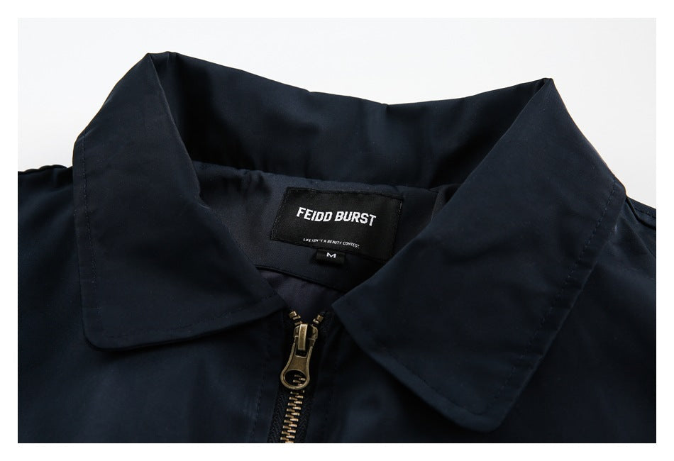 Close-up of a navy jacket collar, metal zipper, and sewn-in neck label.