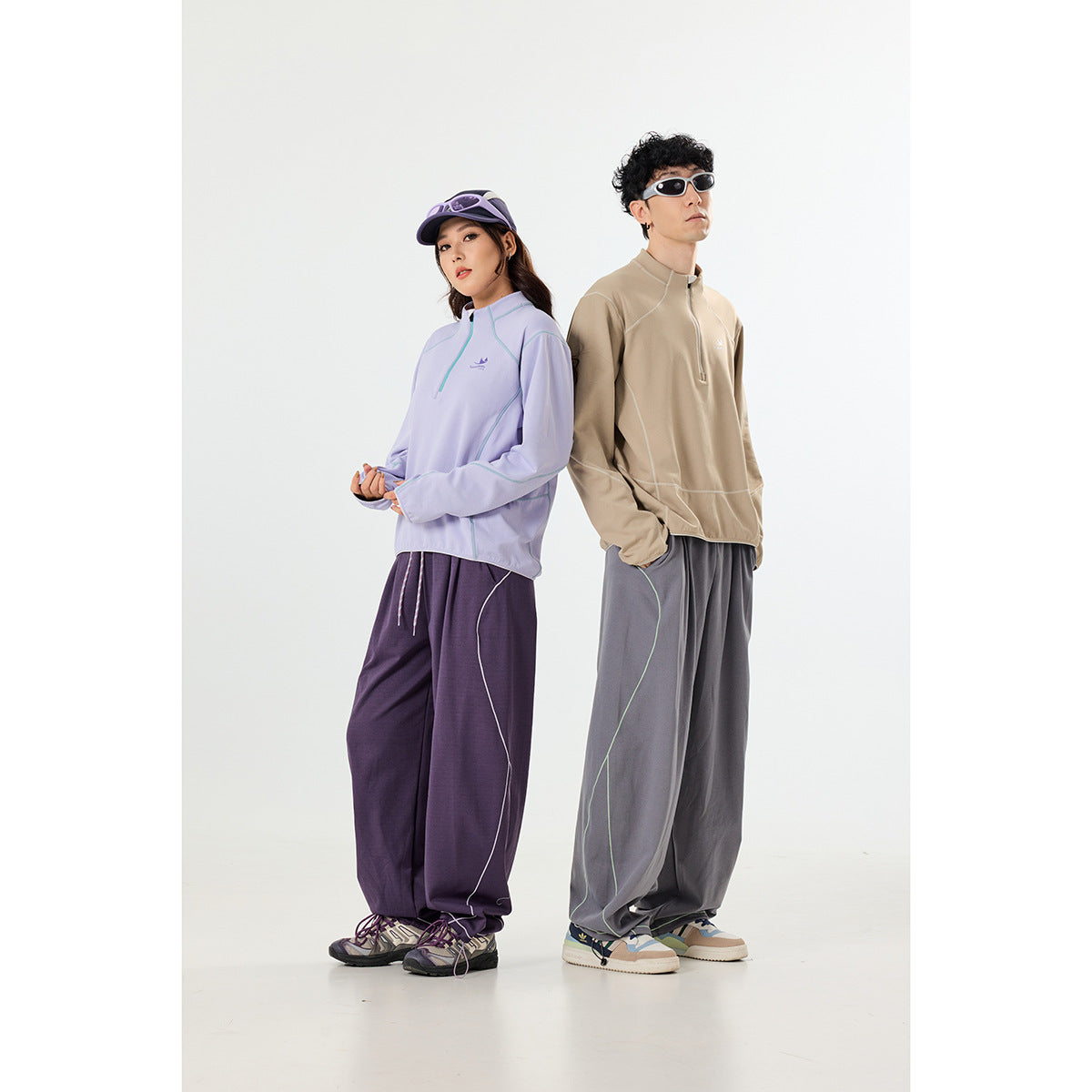 Two models wearing quarter-zip pullovers: lavender with purple pants and beige with gray pants.