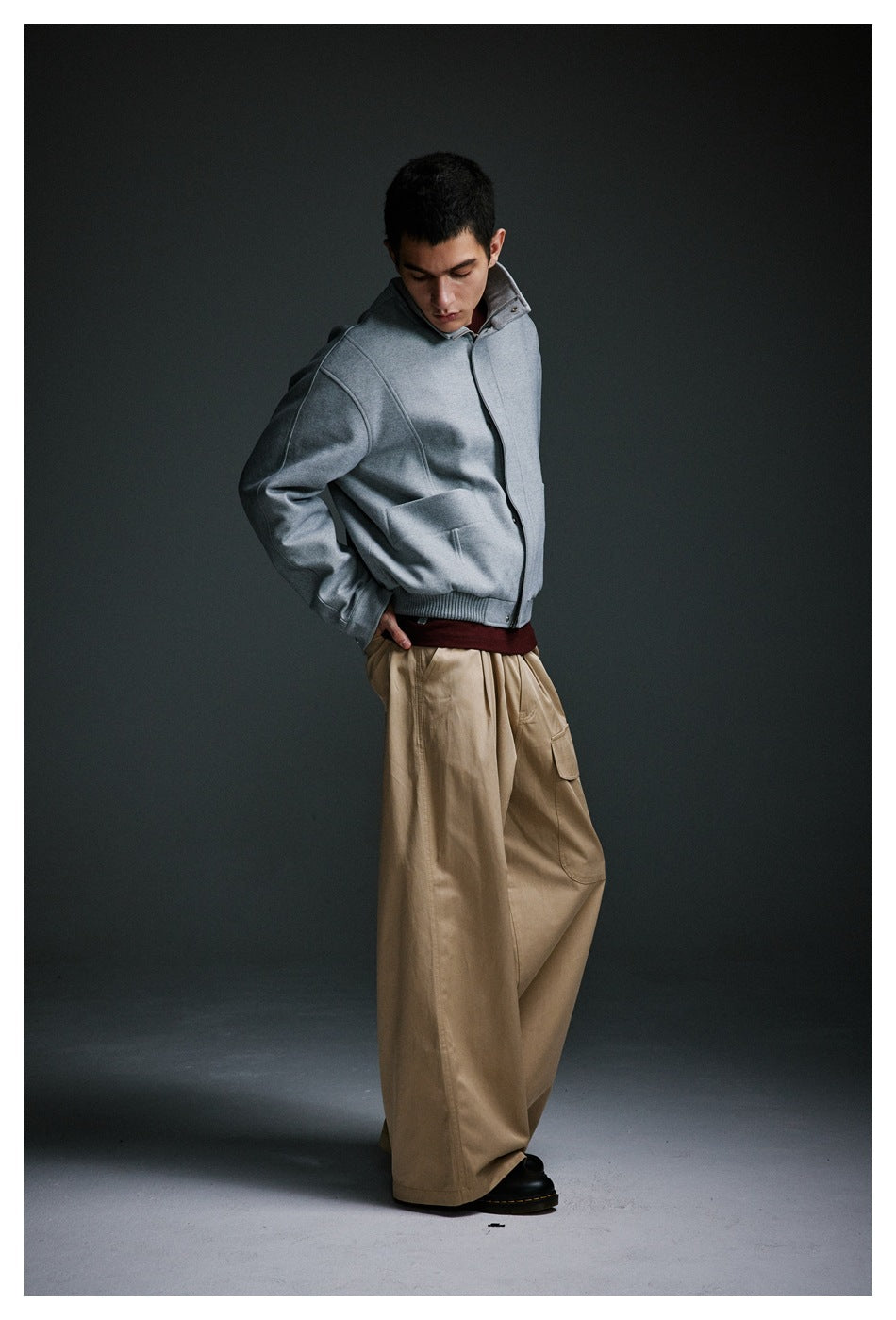 Model wearing a light gray jacket with wide beige trousers, shown at a slight angle.