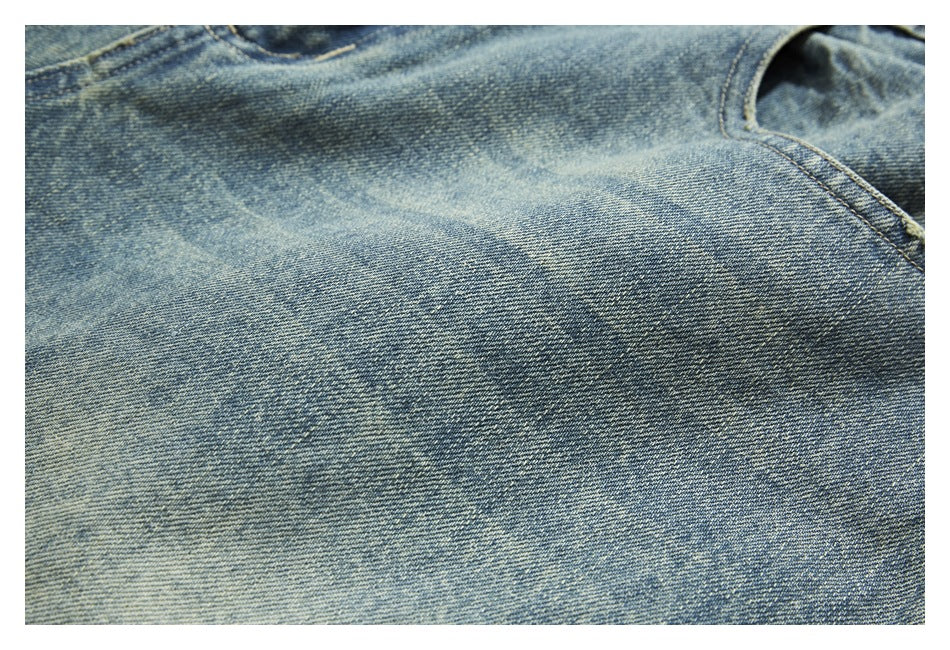 Close-up of washed blue denim showing faded areas and a curved stitched seam.