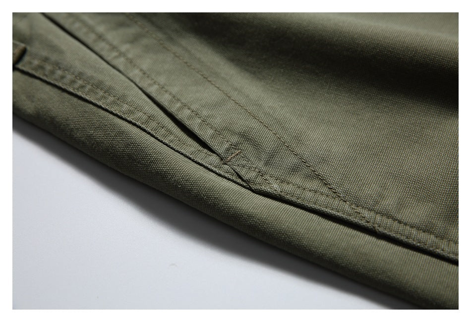 Close-up of olive trouser fabric with a folded seam and parallel stitching.