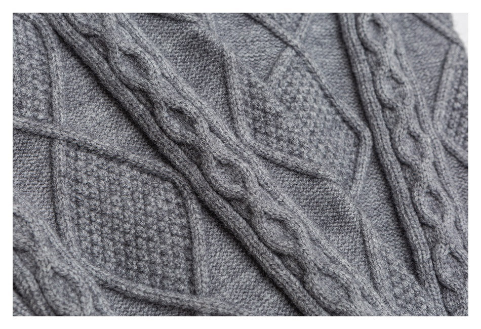 Close-up of gray knit with raised cable-knit bands and textured stitch panels.