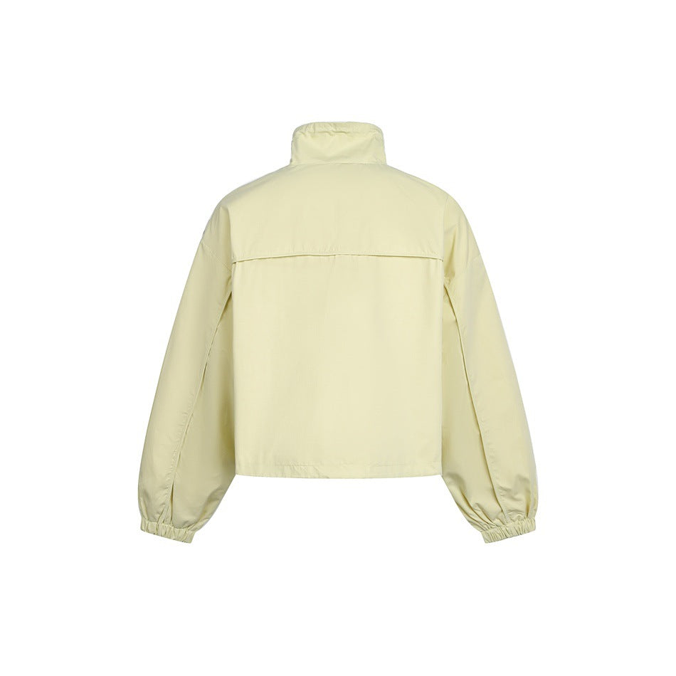 Back view of a pale yellow cropped jacket with a high collar, back yoke and elasticated cuffs.