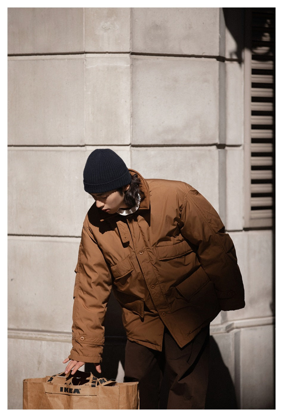 Model leaning forward in the brown hooded jacket, with its front flap pockets visible.