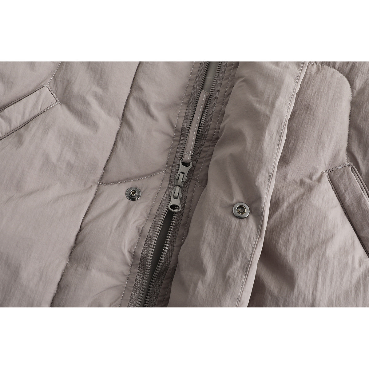 Close-up of a taupe jacket's double zipper, snap closures, and front flap.