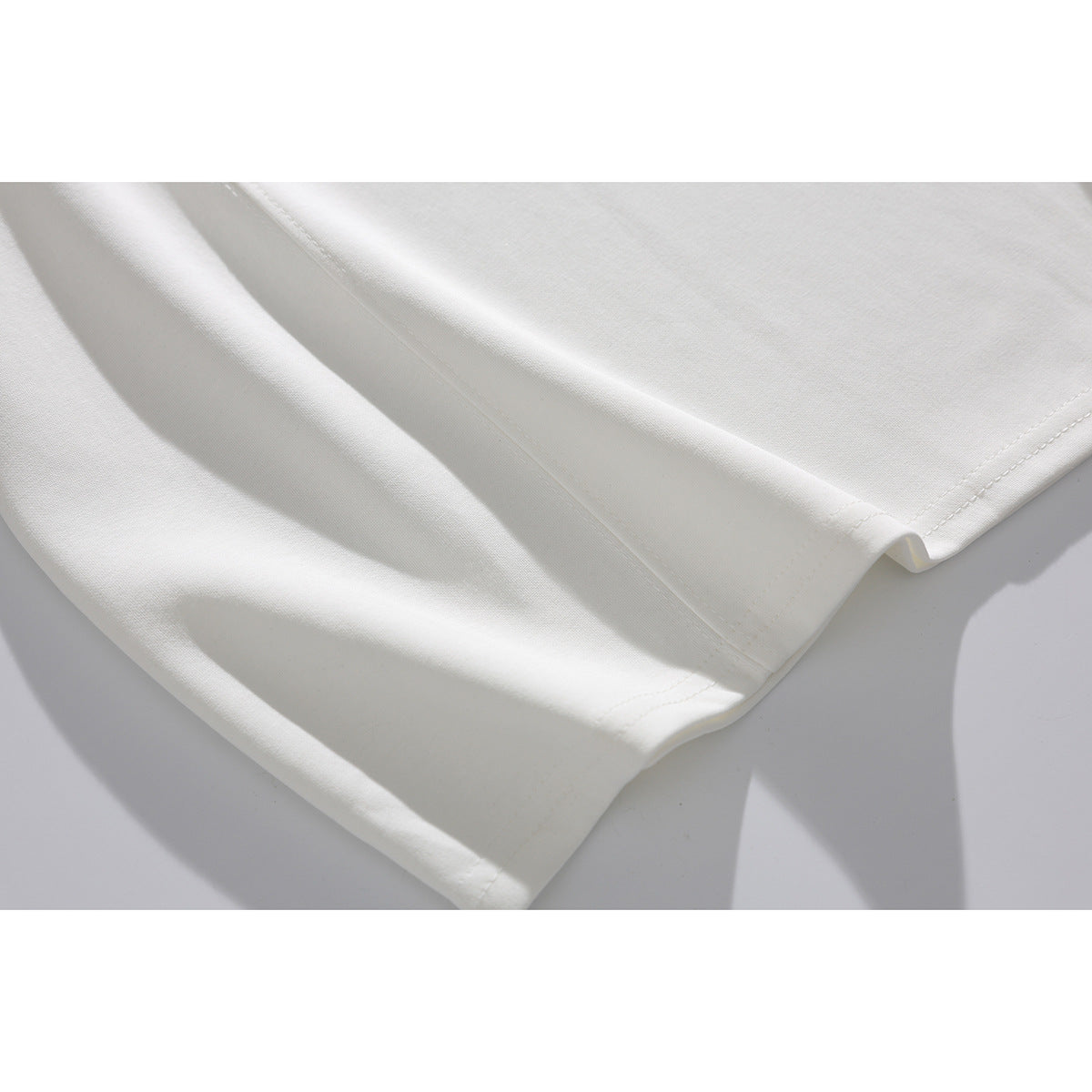Close-up of the white T-shirt's fabric and double-stitched hem.