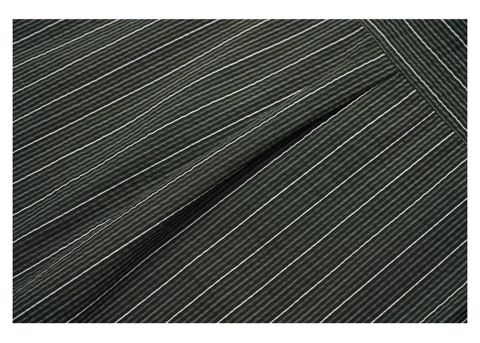 Close-up of dark fabric with fine white stripes gathered into a diagonal fold.