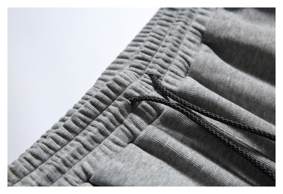 Close-up of the gathered elastic waistband and dark drawstring on gray jogger pants.