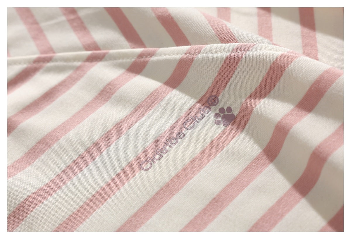 Close-up of cream fabric with dusty pink stripes and a printed text-and-paw motif.