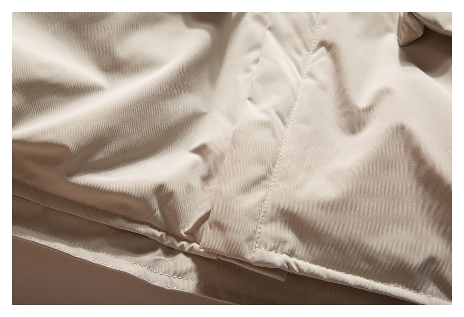 Close-up of the beige jacket's lower seam and stitched hem.