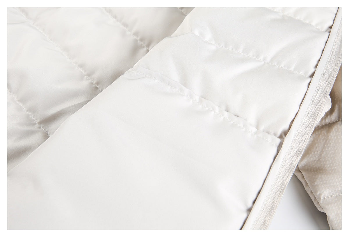 Close-up of ivory padded jacket lining with stitched quilting and a zipper edge.