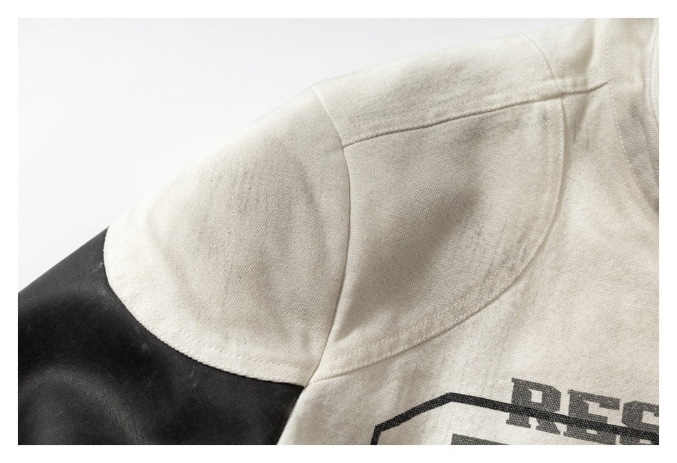Close-up of an off-white jacket shoulder and collar beside a black sleeve, with part of a dark printed graphic visible.