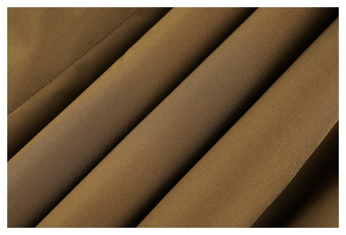 Close-up of brown fabric folded into ridges, showing its fine woven texture and a stitched seam.