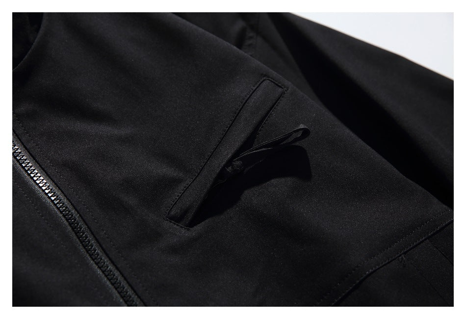 Close-up of a black jacket's angled flap pocket beside the front zipper.