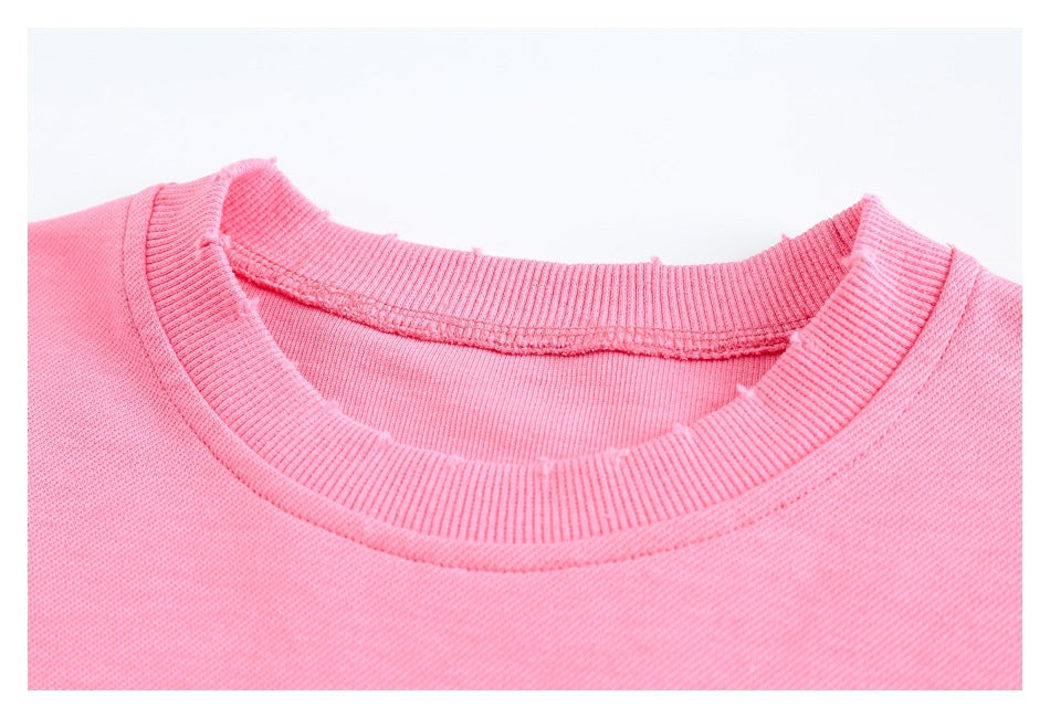 Close-up of a pink sweatshirt’s ribbed crewneck collar and inner neckline stitching.