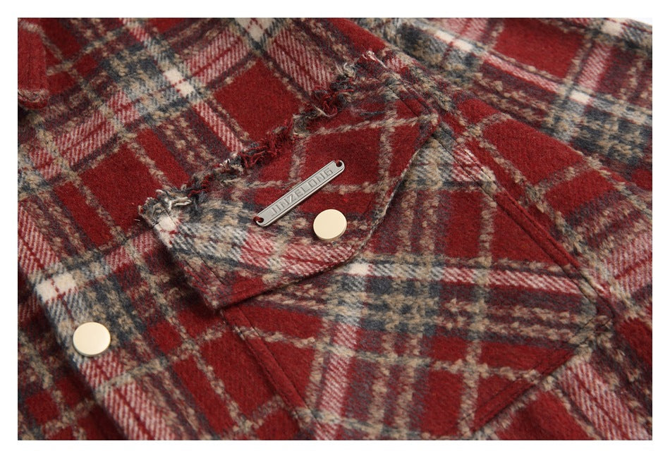 Close-up of a plaid chest pocket with a pale button and a small metal garment tag.