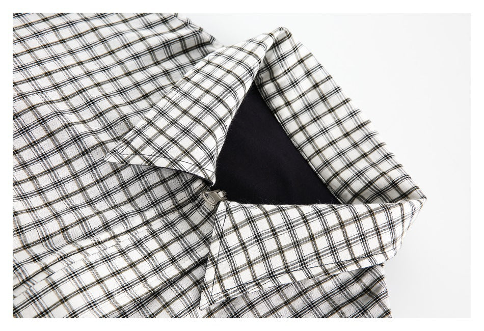 Close-up of a white-and-black plaid garment opened to show a zipper and dark inner fabric.