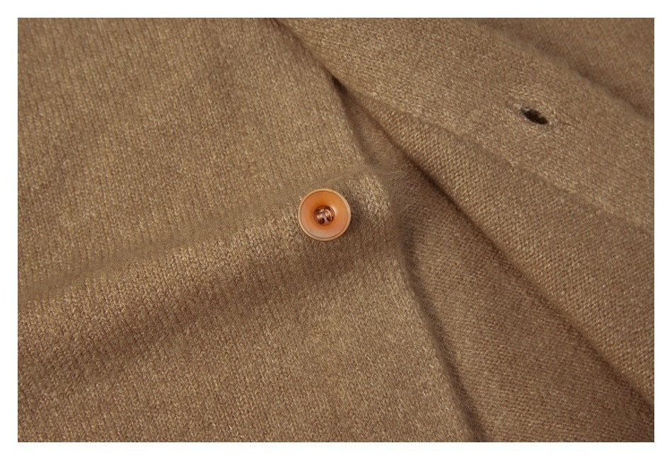 Close-up of a brown button and buttonhole on the tan knit sweater.