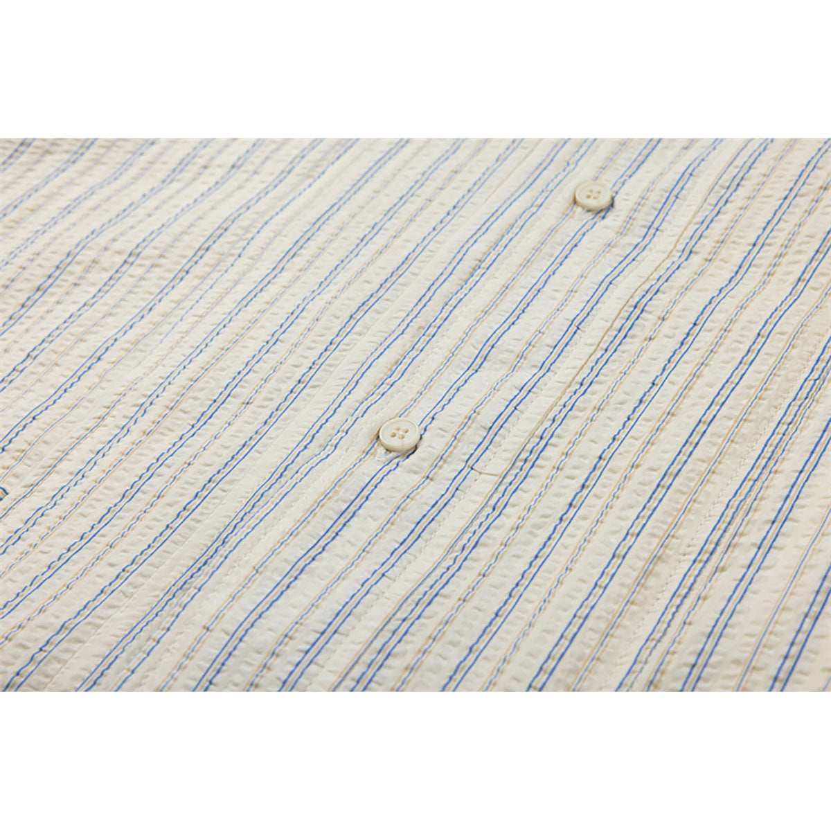 Close-up of cream fabric with fine blue and tan stripes and two cream buttons.