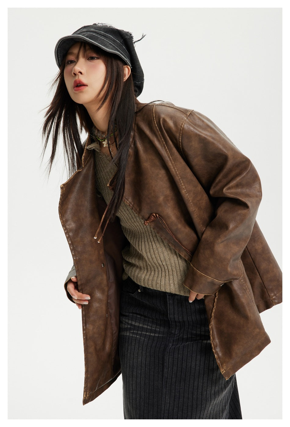 Close view of a model wearing an open brown jacket with knotted cord closures and wide sleeves.
