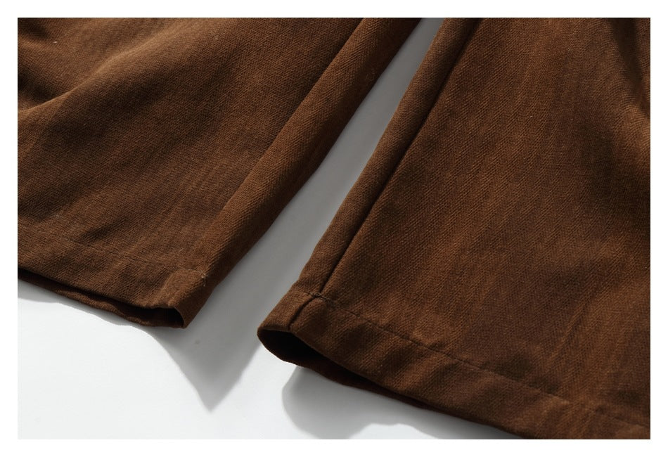 Close-up of the stitched hems on two dark brown trouser legs.
