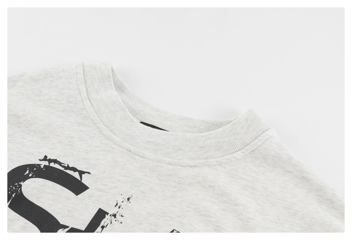 Close-up of the ribbed crew neckline and partial black graphic on a light gray top.