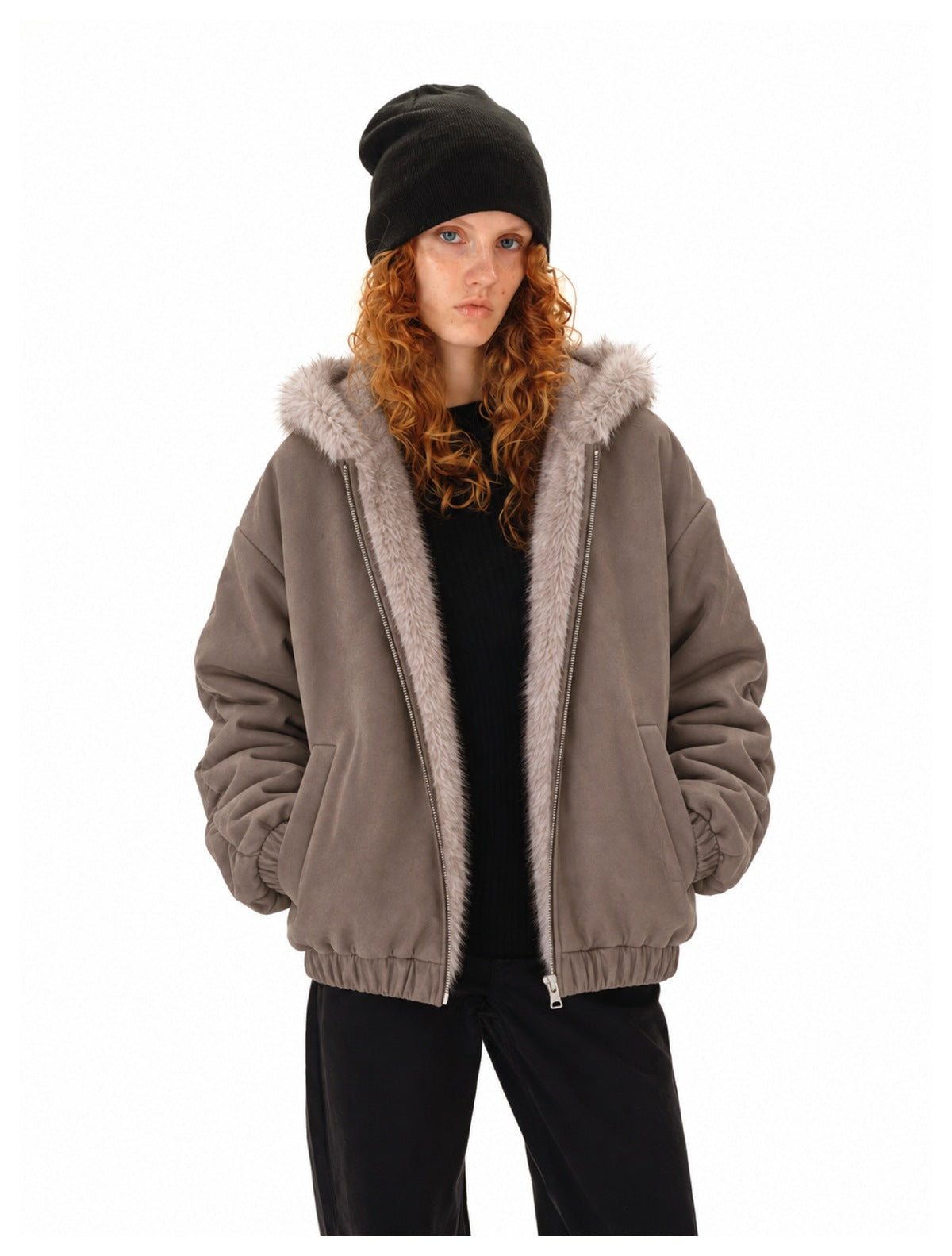 Model wearing an open taupe jacket with a light fur-trimmed hood, styled with a black beanie and trousers.